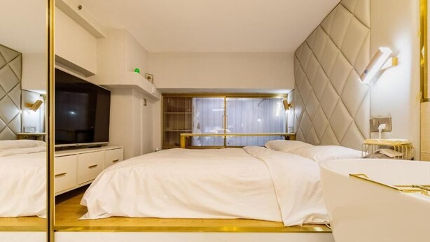 A modern bedroom with a large bed, a TV, and a mirrored wardrobe. - Shanghai Stylish Loft with 2B (Shanghai)