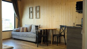 Une pièce chaleureuse avec un mur en bois, un canapé agrémenté de coussins à motifs, une petite table ronde et une chaise noire.