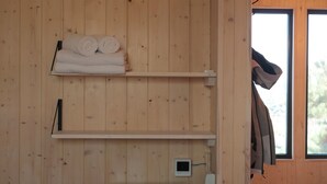 Un intérieur en bois doté de deux étagères : l’une contient des serviettes pliées et l’autre, un petit appareil électronique.