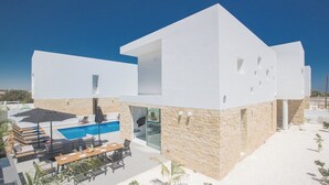 Ett modernt hus med en swimmingpool, utomhusmöbler och en fasad av sten.