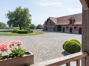 A courtyard with cobblestone paving, a large tree, and a brick building with multiple arches.