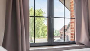 A window with a view of a brick building and trees.