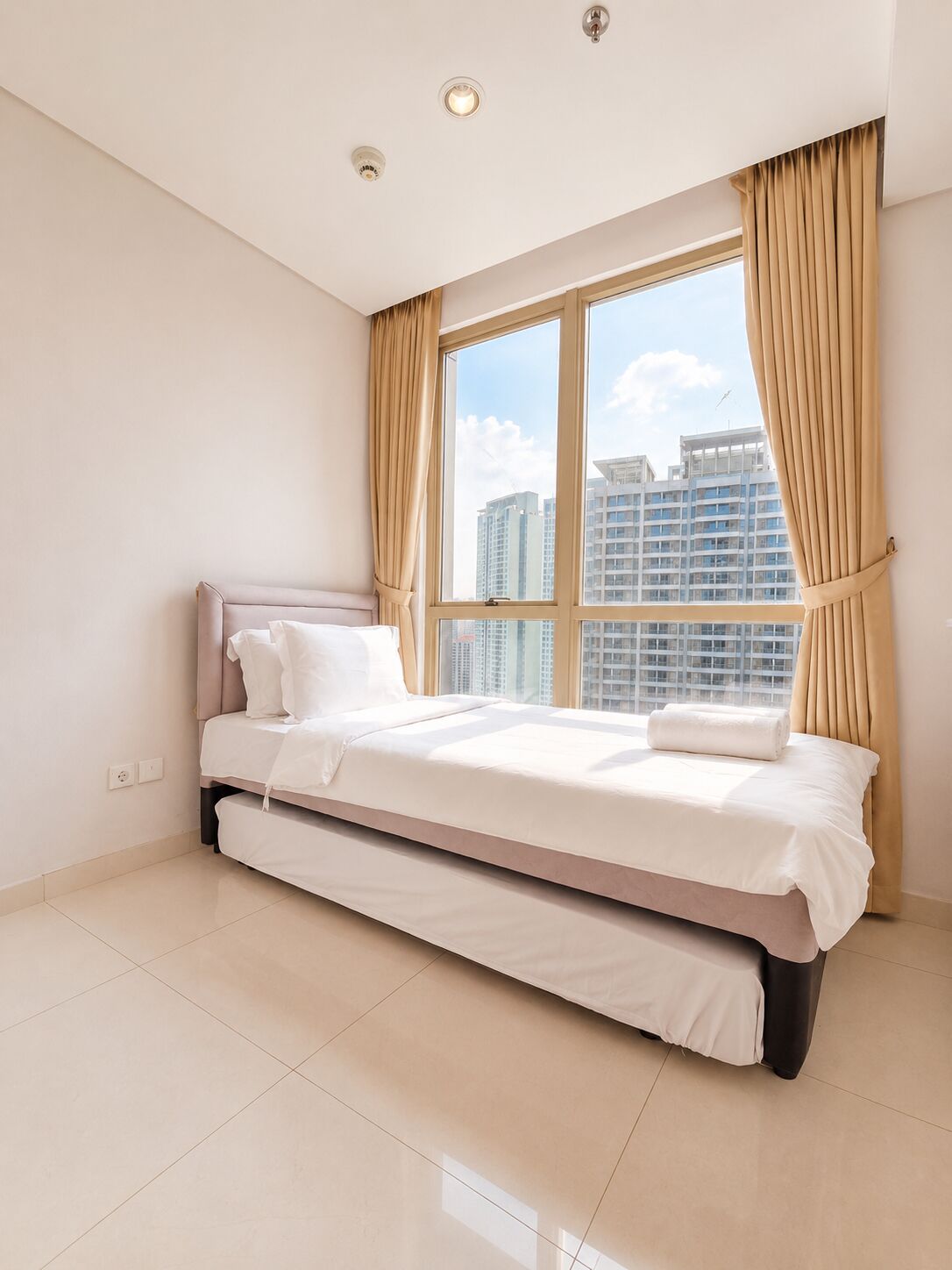 A bedroom with a bed, a window, and a view of buildings.