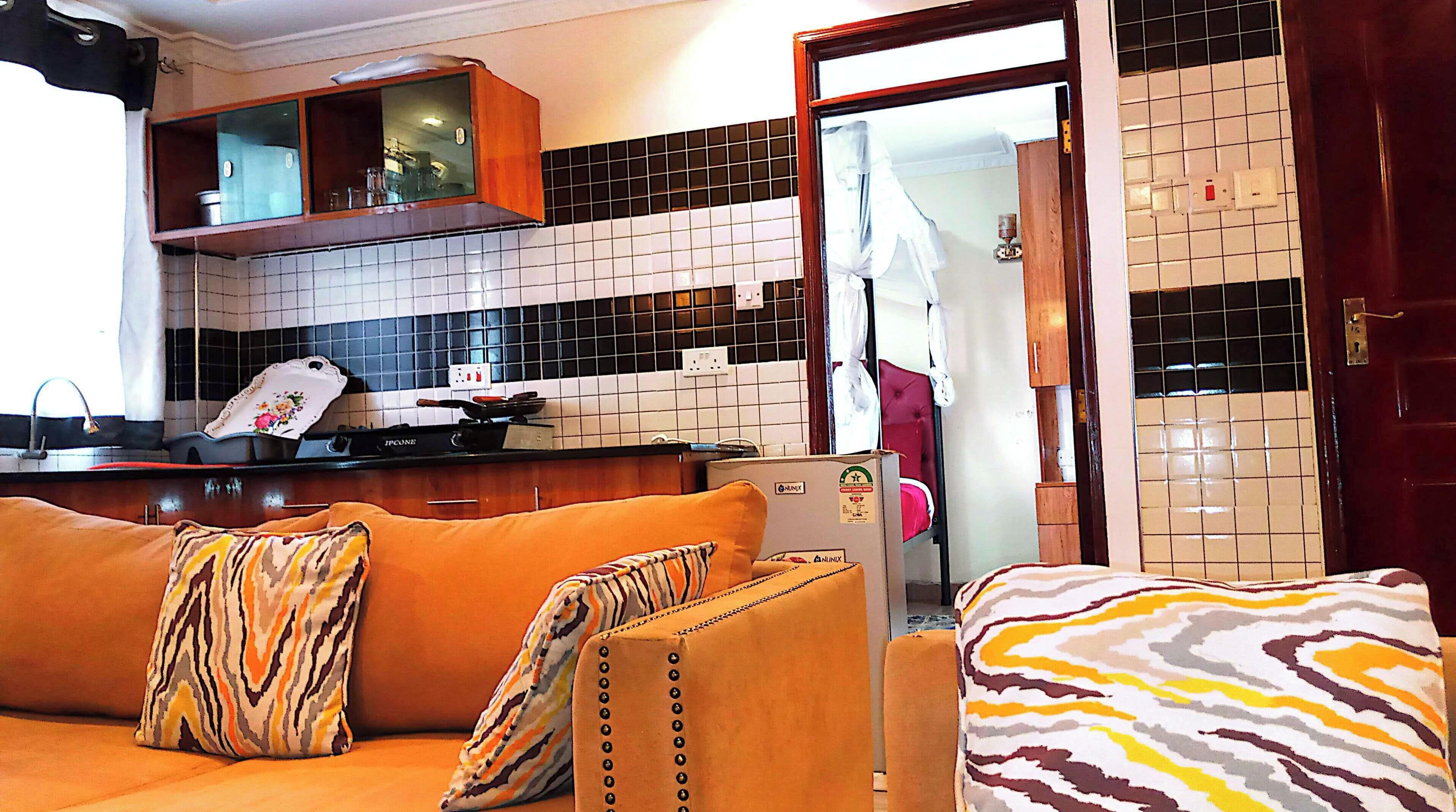 A living room with a sofa, a kitchen area with a stove, and a tiled backsplash.