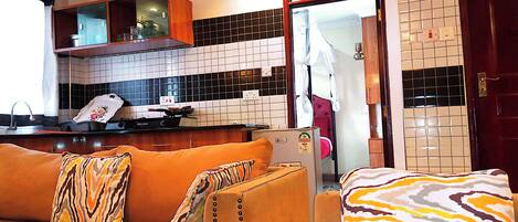 A living room with a sofa, a kitchen area with a stove, and a tiled backsplash.