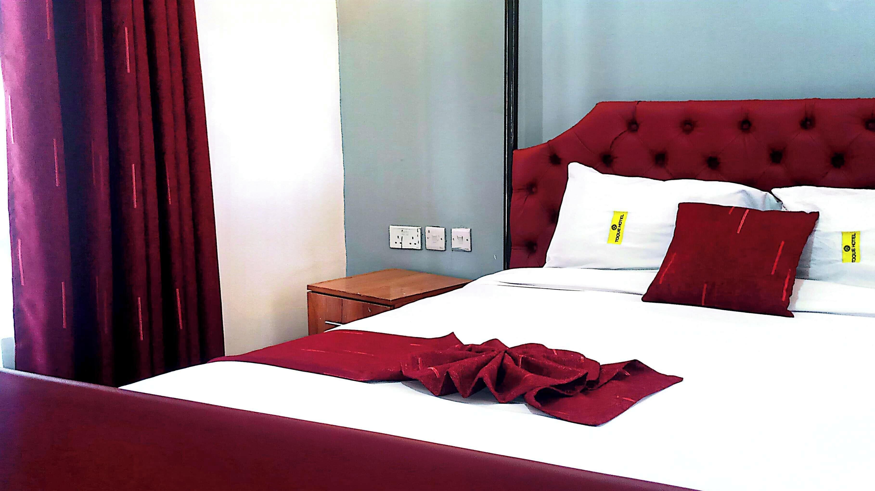 Une chambre d’hôtel avec un lit, une table de chevet et une fenêtre avec des rideaux.