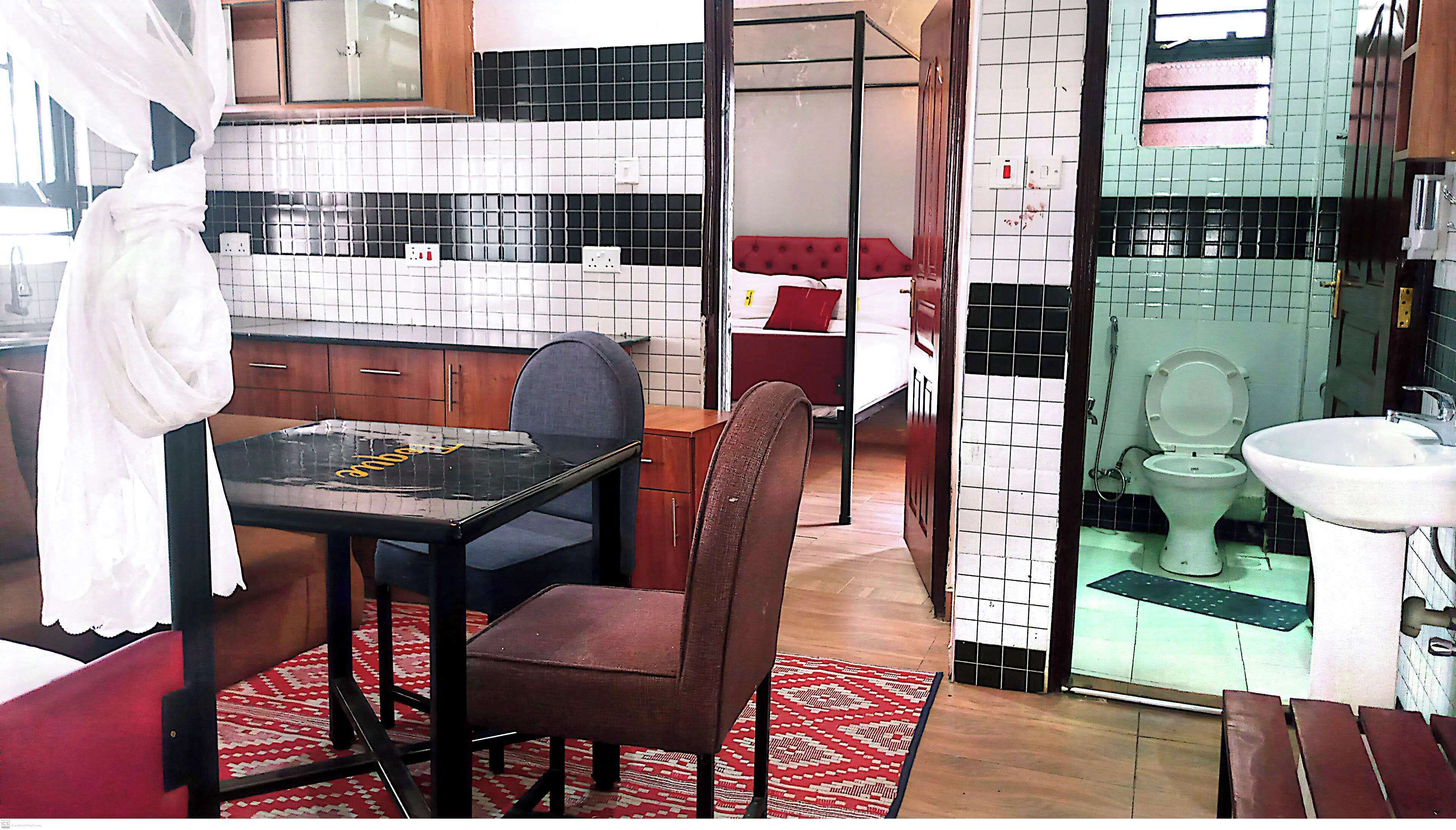 A compact kitchen with a dining area, a small bed, and a bathroom with a toilet and sink.