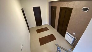 Eine Treppe mit Handlauf, zwei Türen und einem Heizkörper an der Wand.