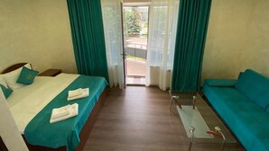Ein Hotelzimmer mit Bett, einer Sitzecke, einem kleinen Tisch und Blick ins Freie.