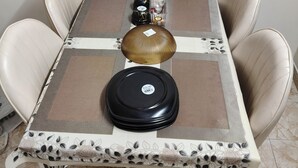 Une table à manger recouverte d’une nappe à motifs, quatre chaises et un ensemble de bouteilles décoratives.