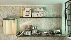 Une cuisine équipée d’un chauffe-eau, d’une bouilloire, d’une cocotte-minute et de divers ustensiles de cuisine posés sur le plan de travail.