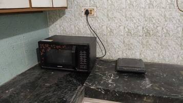 Forno de microondas sobre bancada preta com régua de energia conectada.