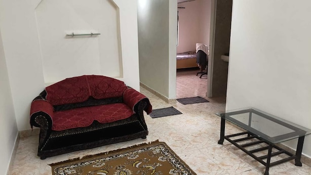 Une pièce avec un canapé rouge, une table en verre et un tapis à motifs.