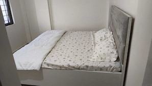 Un lit simple avec une couvre-lit à motifs floraux et un oreiller blanc.