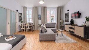 Een moderne woonkamer met een bank, een eettafel met stoelen, een televisie en een keuken.