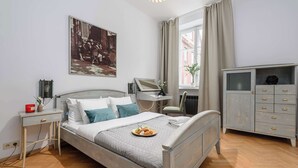 Een keurig opgemaakt slaapkamer met een bed, nachtkastjes, een kaptafel en een raam met gordijnen.