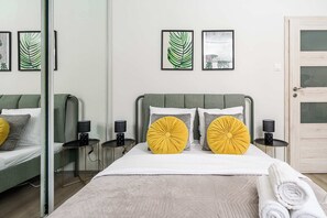 Une chambre d’hôtel avec un lit, des tables de chevet, des lampes et des œuvres d’art accrochées au mur.