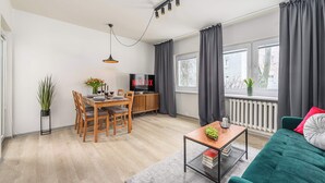 Un salon moderne comprenant un coin repas, un téléviseur et un canapé vert.
