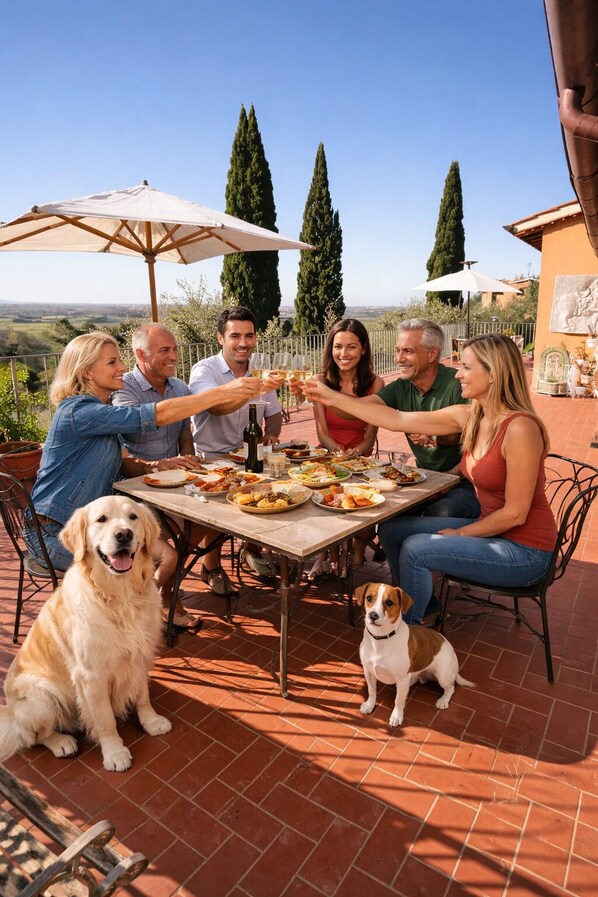 A group of people seated around a table with food and drinks, with a dog sitting in front.