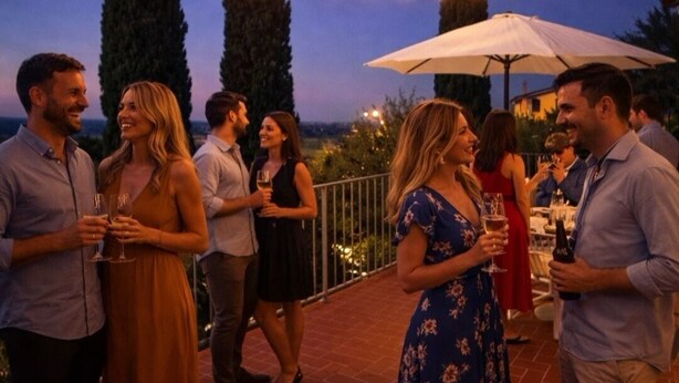 Eine Gruppe von Menschen unterdrückt sich auf einer Terrassenfläche mit Lichterketten und Blick auf die Landschaft.