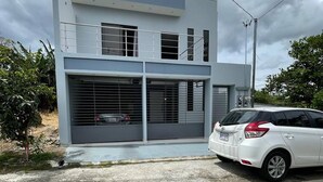A modern two-story building with a garage door and a white car parked in front. - 3 bed 2 Bath 15 min From Airport (San Juan)