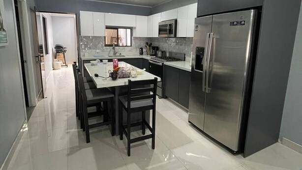 A modern kitchen with a dining area, stainless steel appliances, and a tiled floor. - 3 bed 2 Bath 15 min From Airport (San Juan)