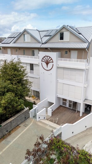 A multi-story building with a prominent logo on the facade, a covered outdoor area, and a staircase leading to the entrance.