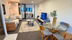 Una sala de estar moderna con un sofá, una mesa de centro de vidrio y un televisor.