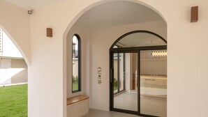 An arched doorway leading to a reception area with a bench and a wall-mounted light fixture. - Taupe Hotel (Chiang Mai)