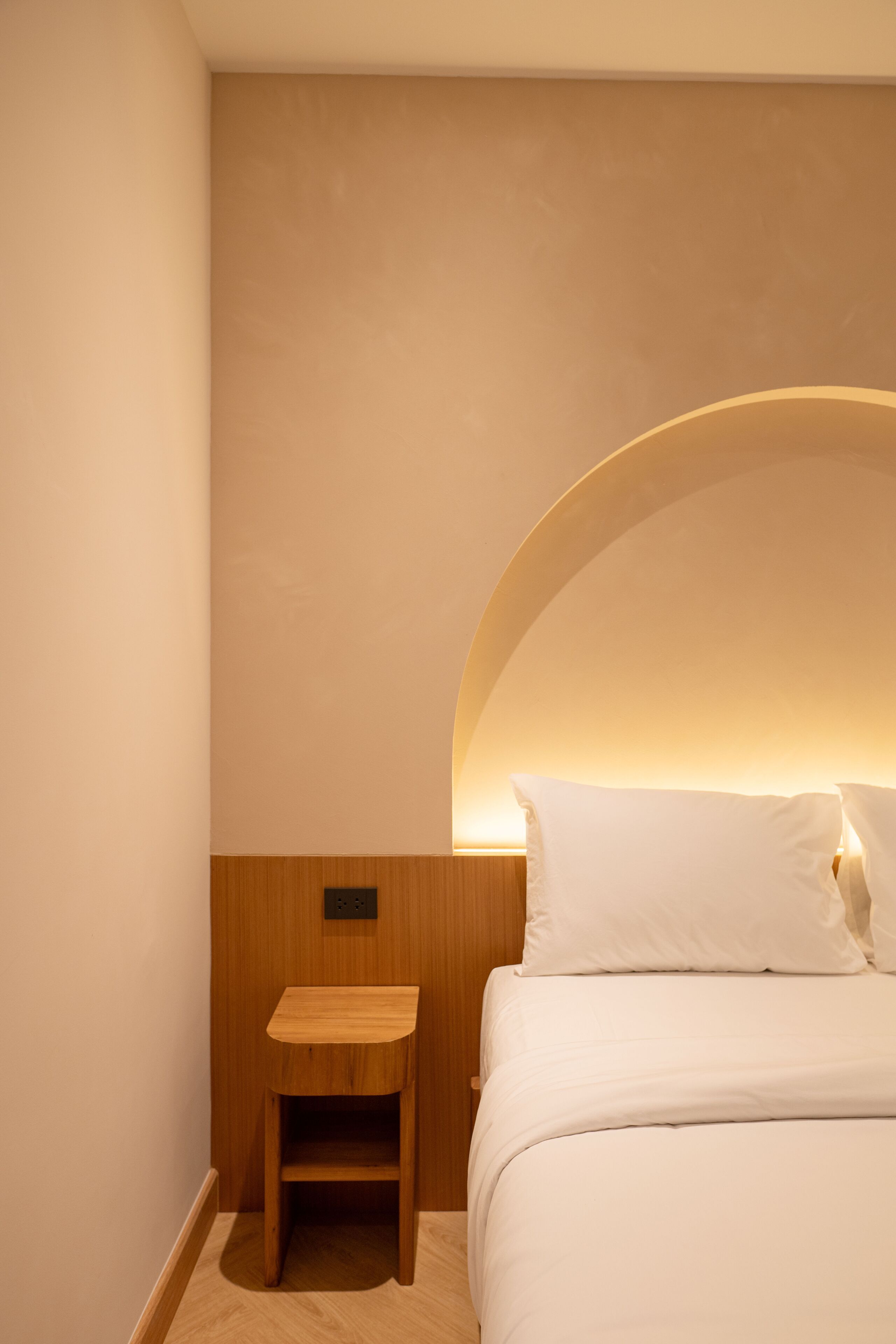 A bedroom with a bed, a nightstand, and a wall-mounted light fixture.