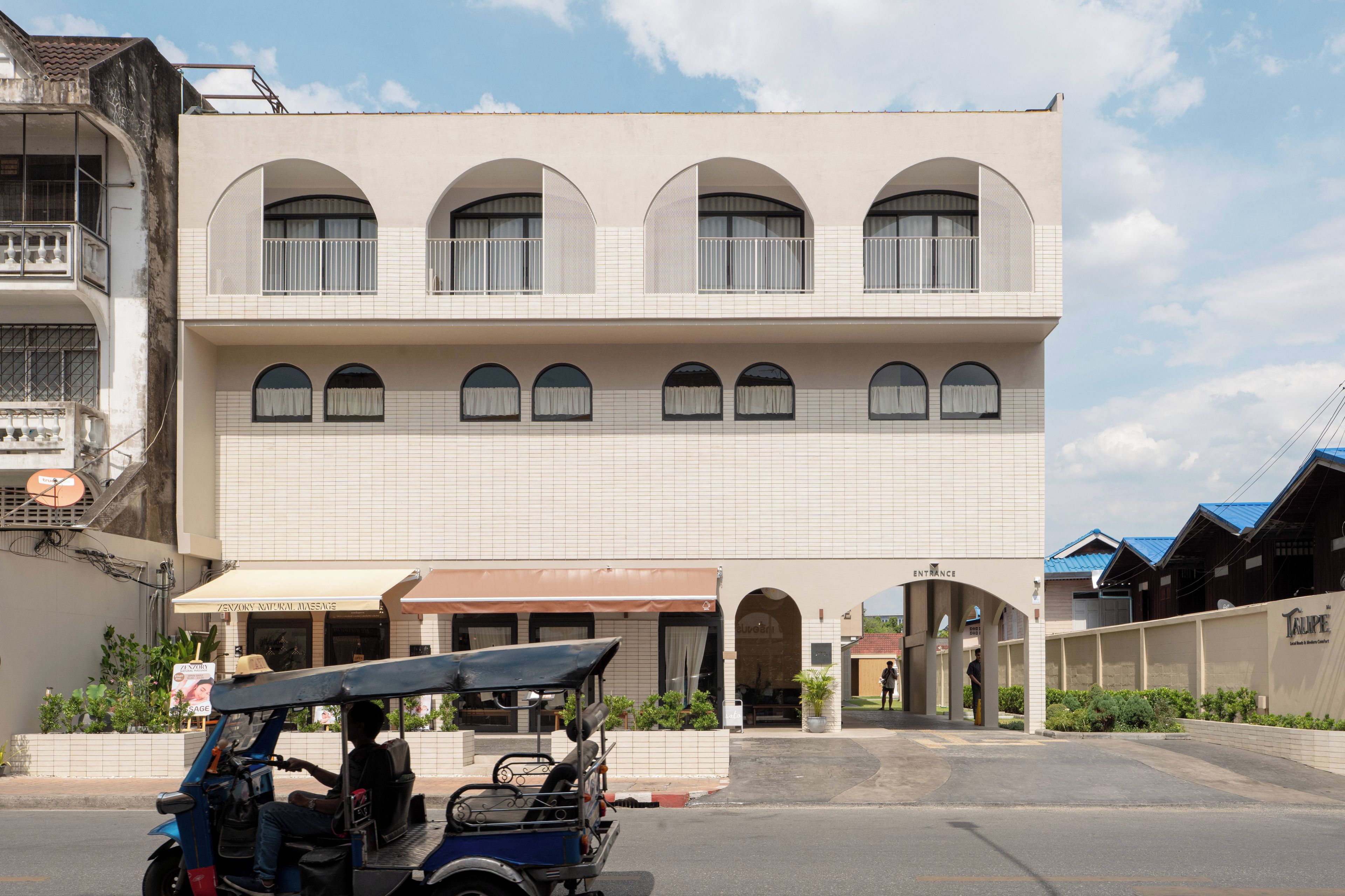 A multi-story building with a central entrance, large windows, and a covered area with signage for a massage service.