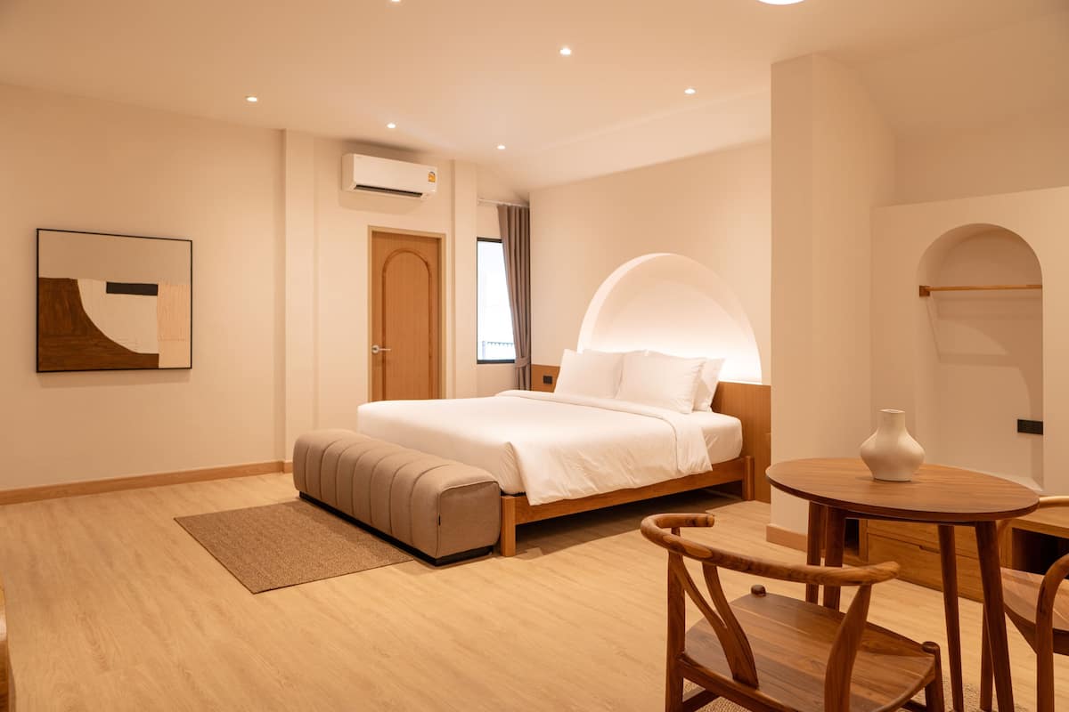 A modern bedroom with a bed, a bedside table, a chair, and a wall-mounted artwork.