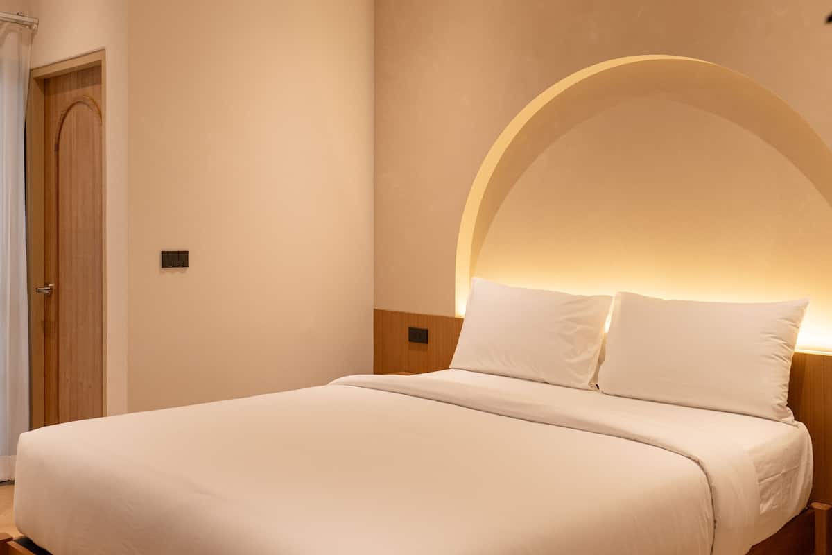 A modern bedroom with a wooden bed, a curved wall design, and a wooden floor.