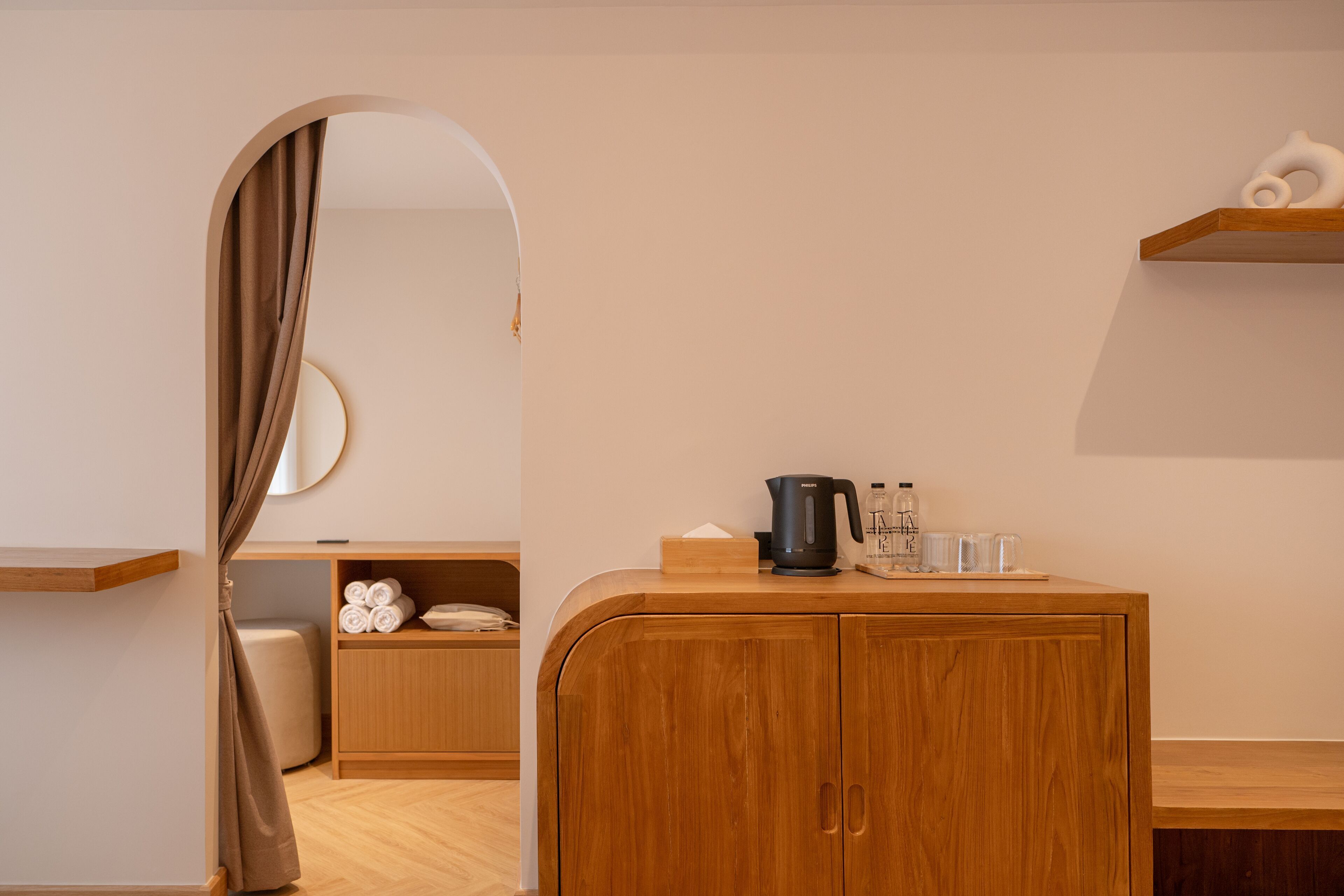 A modern bathroom with a wooden vanity, a mirror, a towel rack, and a shower area.