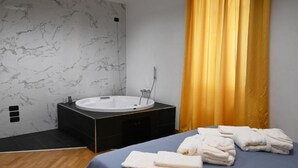 Un bagno moderno con parete in marmo, una vasca da bagno ampia e un mobile lavabo nero.