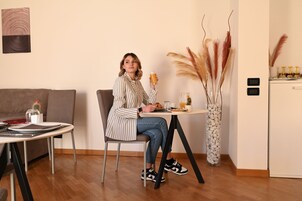 A person sitting at a table with a cup, a plate with food, and a vase with plants.