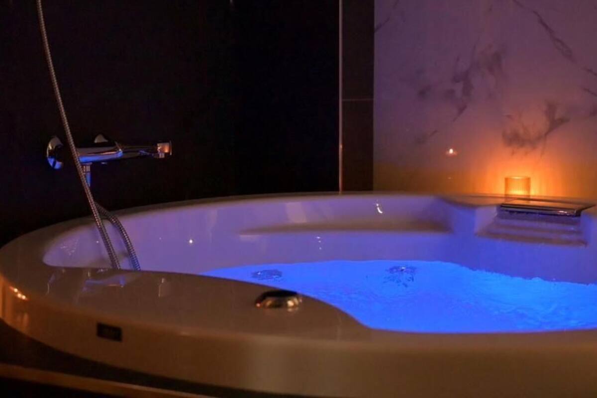Een whirlpool met ingebouwde verwarming, een handdouche en een klein tafeltje.