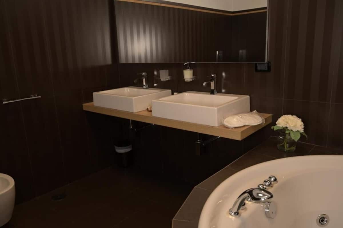 Een moderne badkamer met twee wasbakken, een badkamermeubel en een bad.