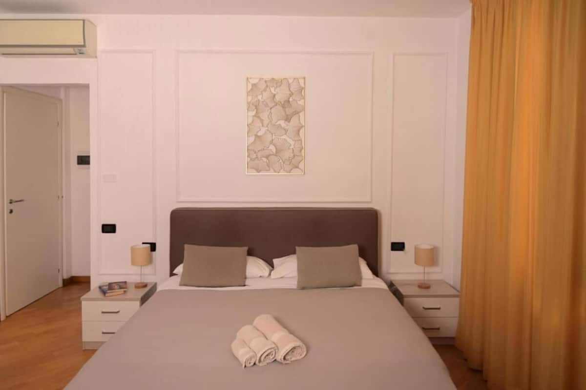 Een netjes ingerichte slaapkamer met een groot bed, twee nachtkastjes en een kunstwerk aan de muur.