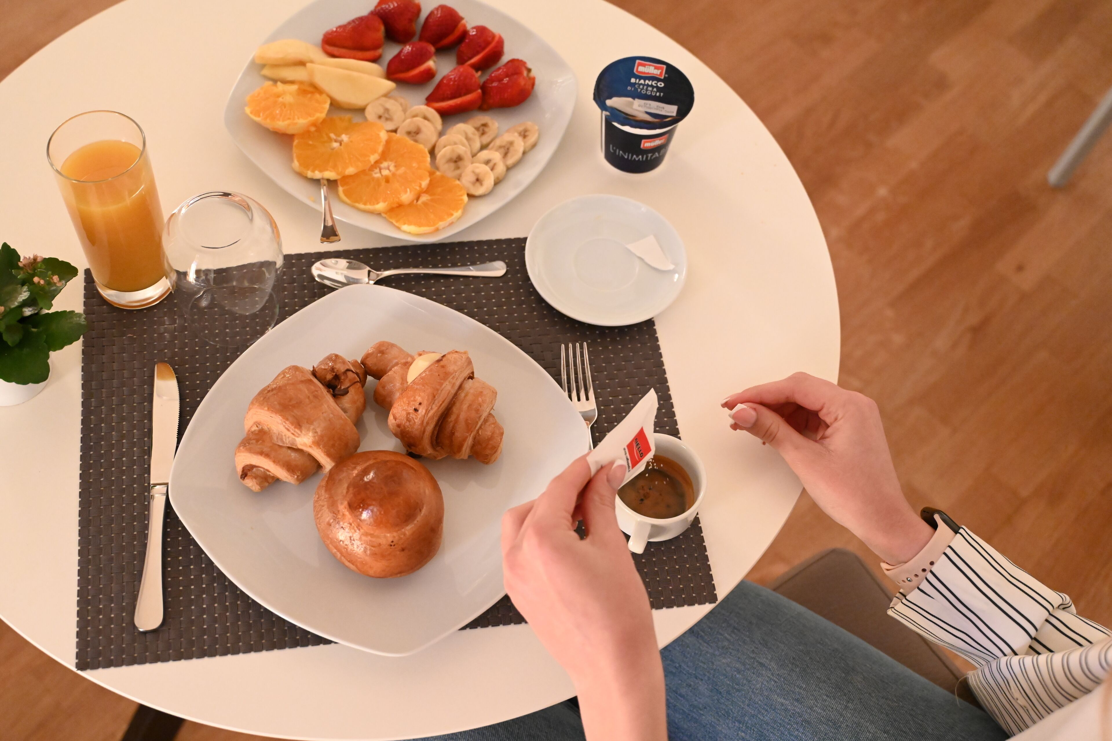 Un desayuno con croissants, fruta y una taza de café sobre una mesa.
