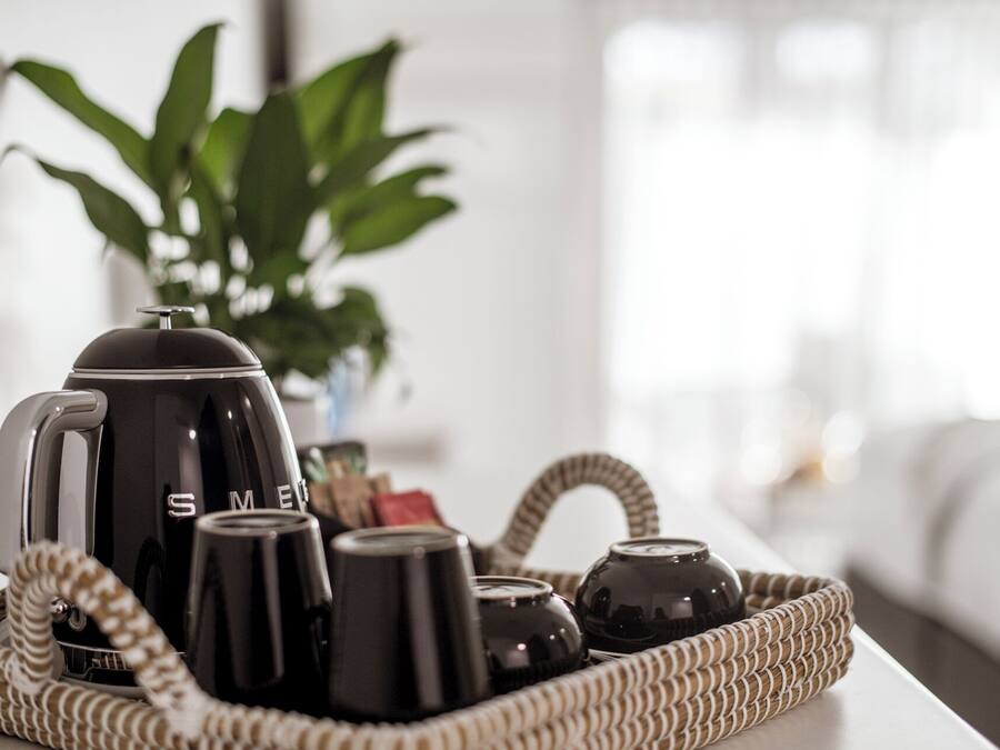 A tray with a coffee maker, cups, and a thermos on a table.