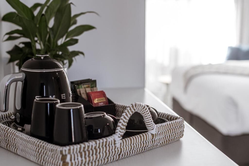 A tray with a coffee maker, cups, and a box of coffee pods on a table.