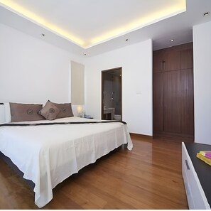 A modern bedroom with a large bed, bedside tables, a wardrobe, and a door leading to another room. - Lovely studio with AC in charming Tambon Kamala (Tambon Kamala)