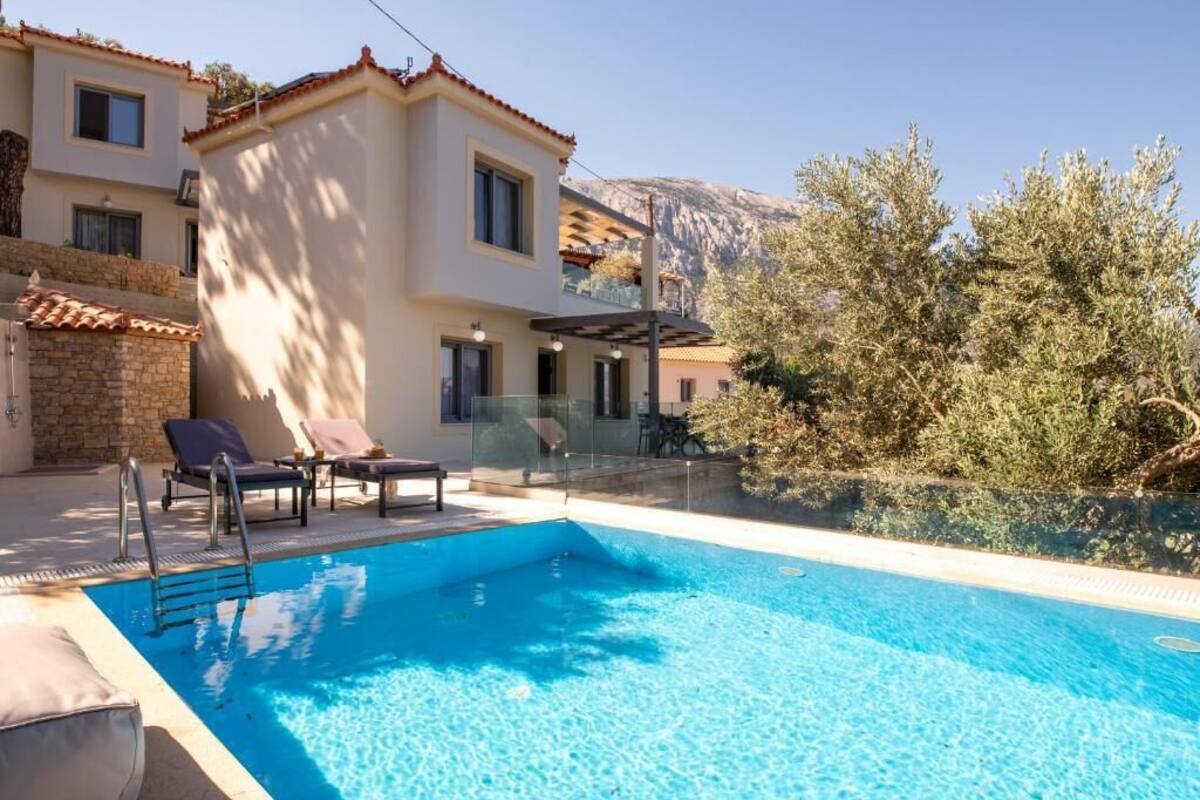 A swimming pool with lounge chairs, a glass balustrade, and a mountain backdrop.