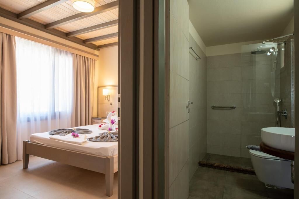 A hotel room with a bed, a bathroom with a shower, and a toilet.