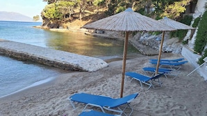 Une plage avec des chaises longues bleues et un parasol en paille.