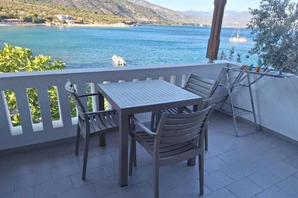 A terrace with a table and chairs, overlooking a body of water and hills.