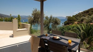 Une terrasse avec une table, des chaises et une vue sur un lac et des montagnes.