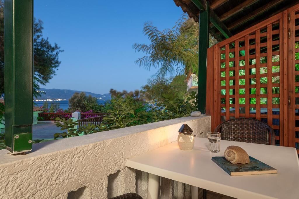 A balcony with a table, a chair, a glass of water, and a book.