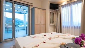 Une chambre d’hôtel comprenant un lit, une porte-fenêtre coulissante donnant sur un balcon, une armoire et un téléviseur.